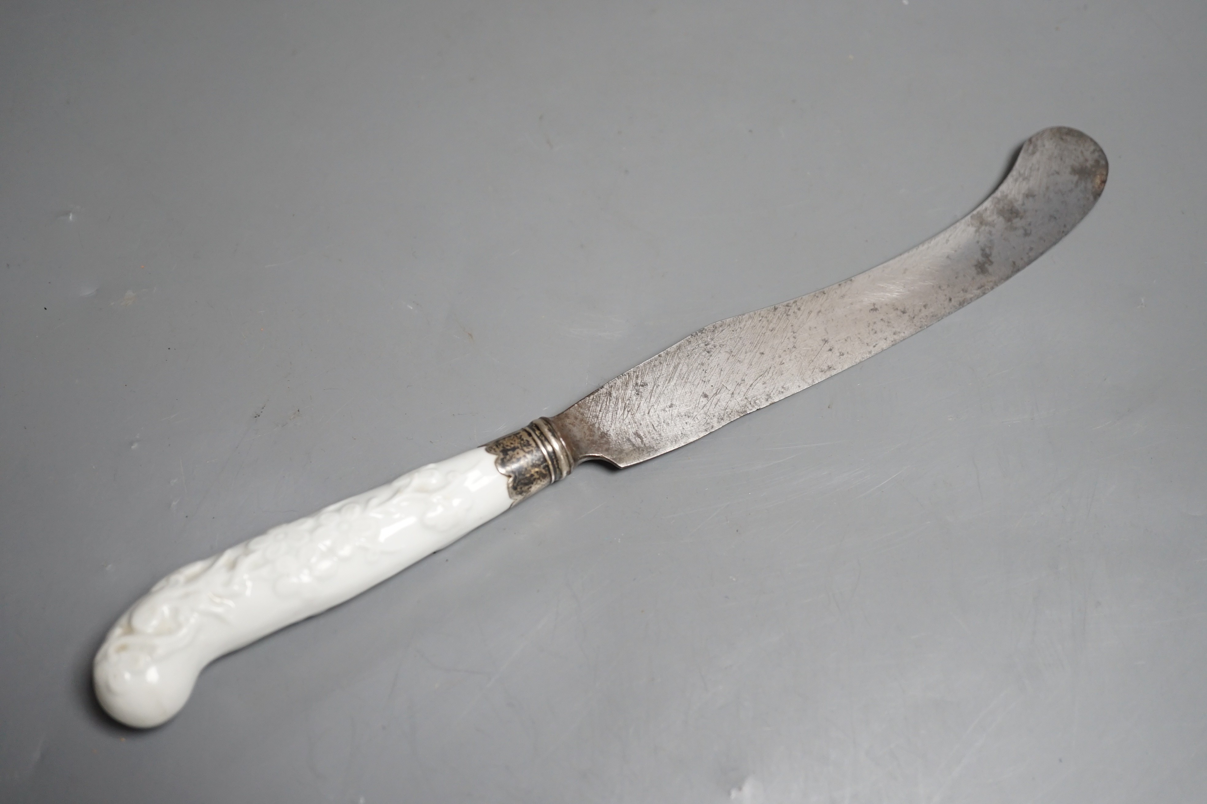 A Chelsea blanc de chine knife handle moulded with entwined branches and flowerheads, with silver ferule, incised triangle period